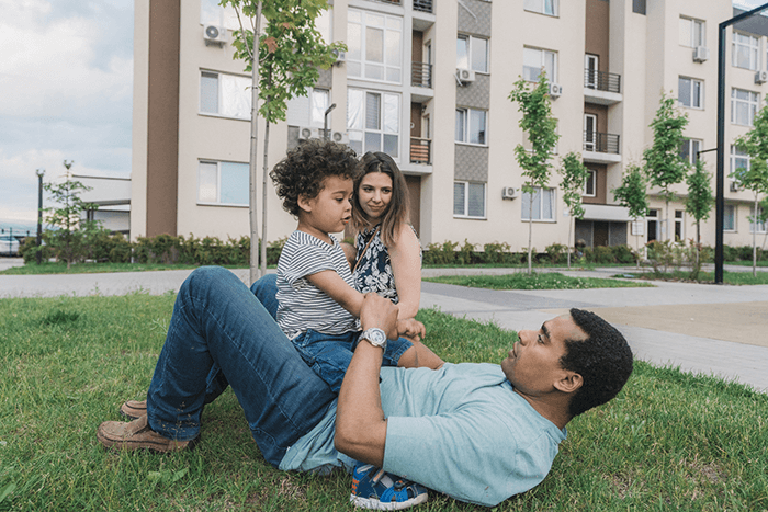 family playing on lawn outside apartment community